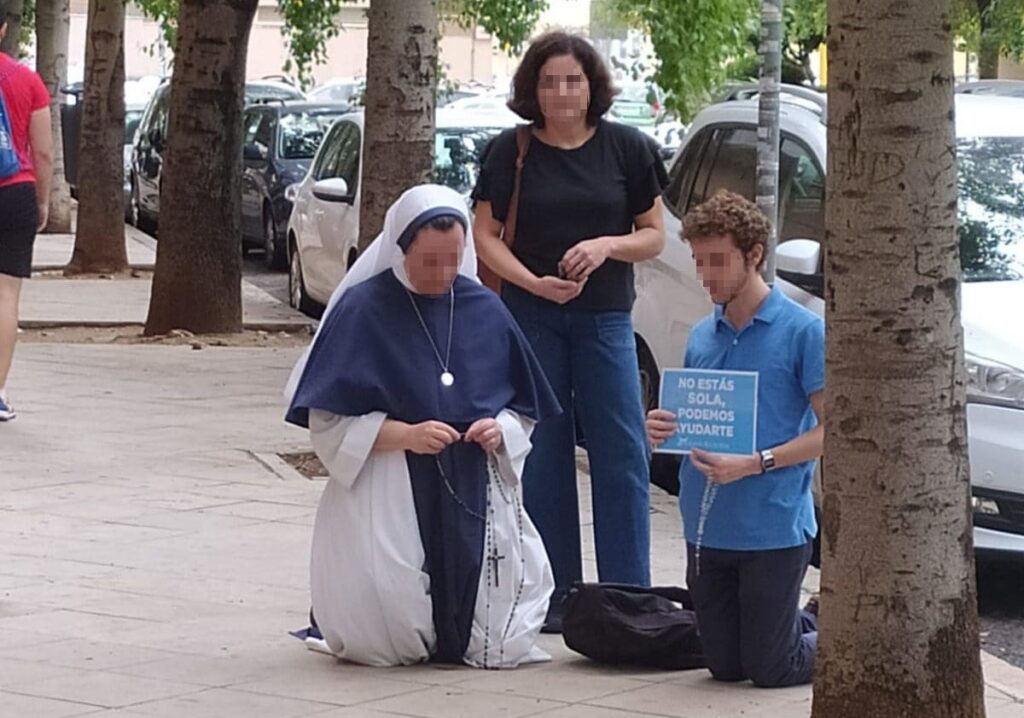 Grupo de personas rezando frente a una clínica de interrupción voluntaria del embarazo.